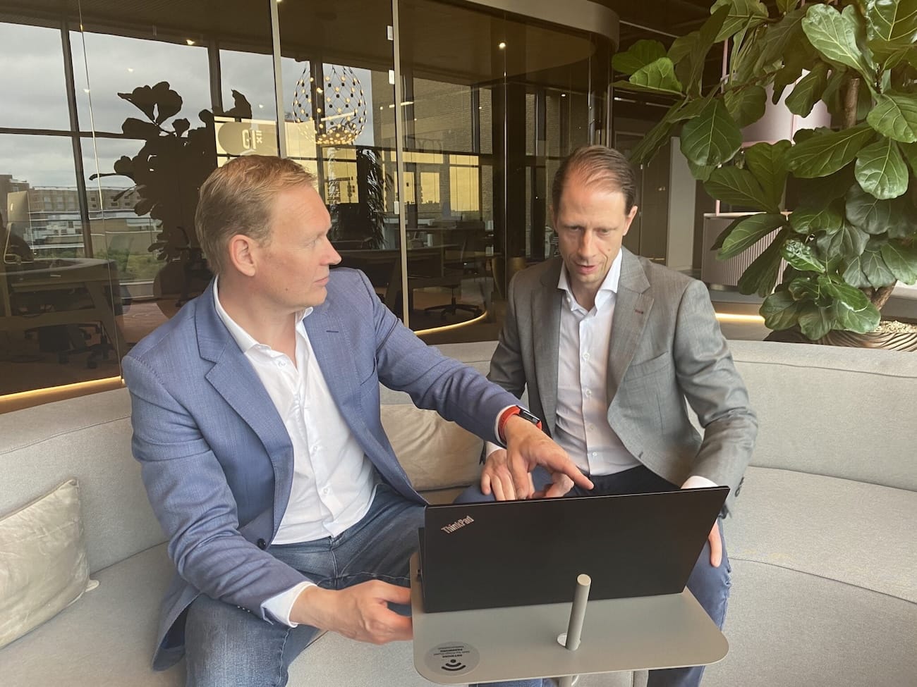 Twee auditors bespreken resultaten van een NEN 7510 audit in een moderne kantooromgeving.